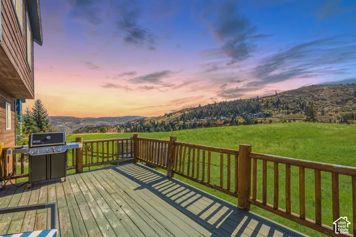Elevated wood deck featuring a log-style railing and unobstructed exposure to mountain and open field scenery