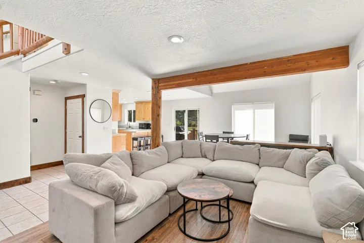Open-concept interior featuring a structural wood beam, recessed lighting, wood-finish flooring, tile flooring, and sliding glass doors