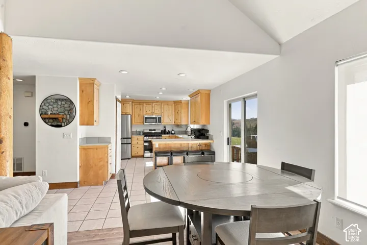 Kitchen featuring light-tone wood cabinetry, recessed lighting, tile flooring, stainless steel appliances, and a peninsula with bar seating