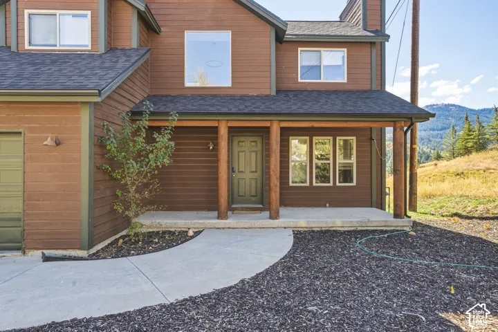 Exterior featuring lap siding, covered porch with exposed timber posts, concrete walkway, and mountain backdrop