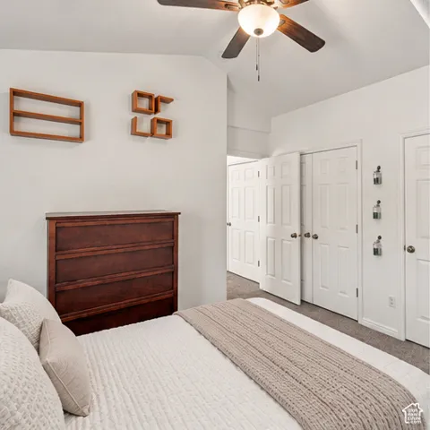 Vaulted ceiling with integrated ceiling fan, neutral carpeting, and multi-panel interior doors