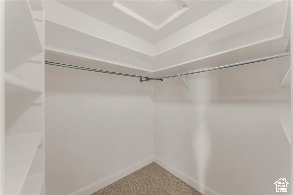 Walk-in closet featuring white built-in shelving, tiered storage surfaces, and metal hanging rods