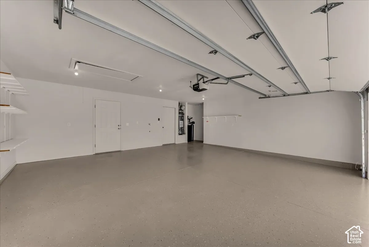 Finished garage featuring epoxy-coated flooring, painted interior walls, integrated ceiling lighting, and built-in wall shelving