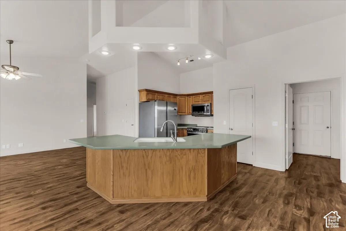 Kitchen featuring an angled island with a solid surface countertop, wood-finish cabinetry, recessed ceiling lighting, and wood-finish flooring