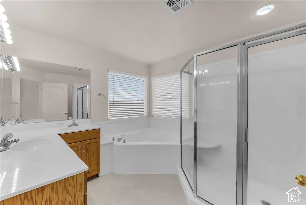 Dual-sink vanity with a solid-surface countertop, corner soaking tub, and a separate glass-enclosed shower with a built-in seat