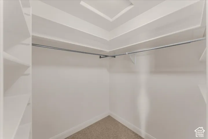 Walk-in closet featuring white built-in shelving, tiered storage surfaces, and metal hanging rods