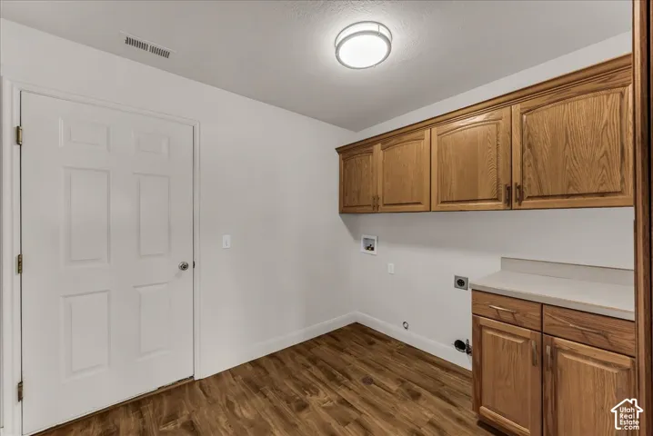 Utility space featuring wood-finish cabinetry, solid-surface countertops, wood-finish flooring, and a flush-mount ceiling light fixture