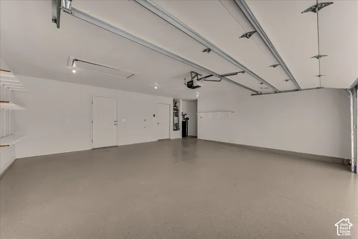 Finished garage featuring epoxy-coated flooring, painted interior walls, integrated ceiling lighting, and built-in wall shelving