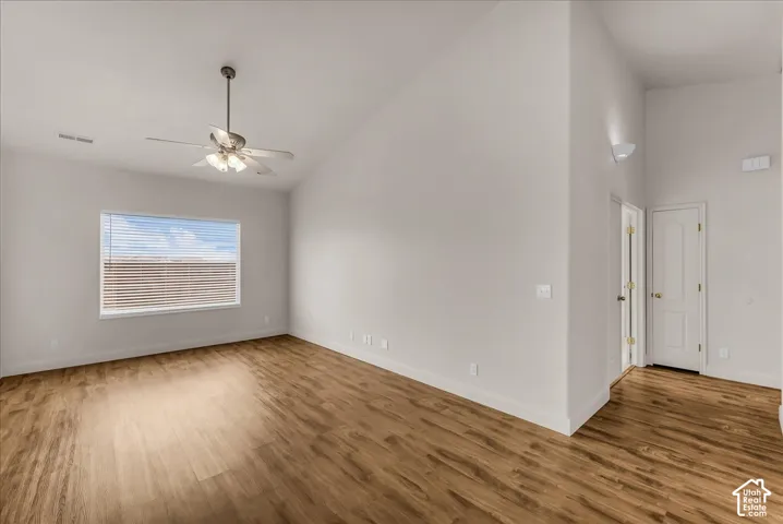Vaulted ceilings, wood-finish flooring, and a ceiling-mounted light fixture with fan