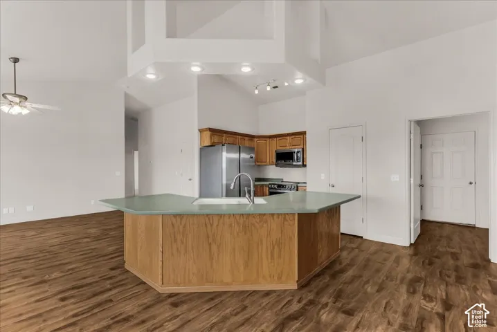 Kitchen featuring an angled island with a solid surface countertop, wood-finish cabinetry, recessed ceiling lighting, and wood-finish flooring