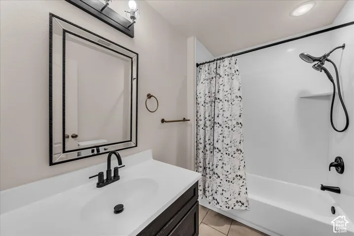 Bathroom featuring a dark wood-finish vanity with a white countertop, rectangular integrated sink, matte black faucet, and matching multi-light fixture