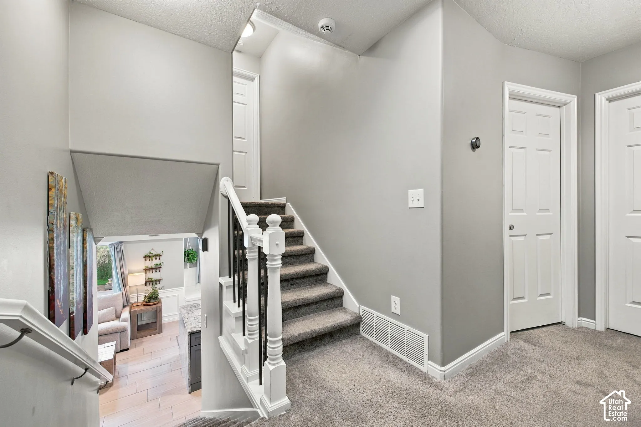 Staircase featuring a white balustrade with metal spindles, neutral carpeting, and solid-core paneled interior doors
