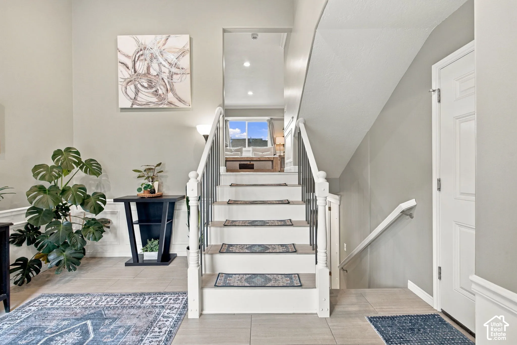 Foyer featuring high ceilings, neutral wall tones, large-format tile flooring, and a staircase with white painted balusters and metal spindles