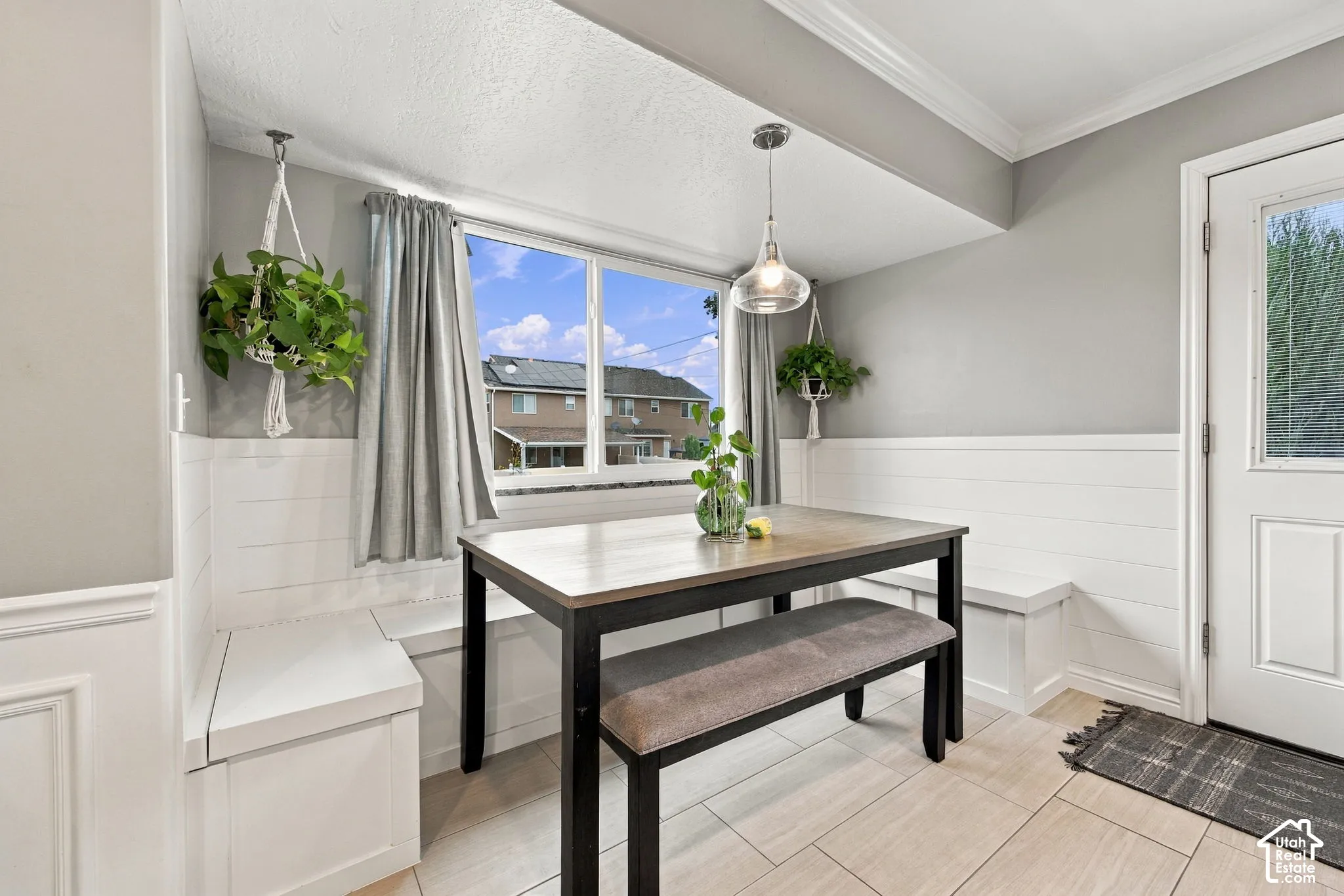 Built-in white bench seating featuring horizontal shiplap detailing, large picture window, and hanging glass pendant light