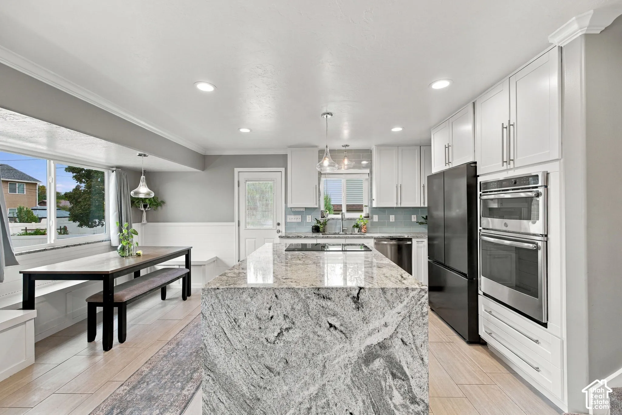 Kitchen featuring a large central island with stone countertop, white cabinetry, built-in double oven, recessed lighting, and wood-finish flooring