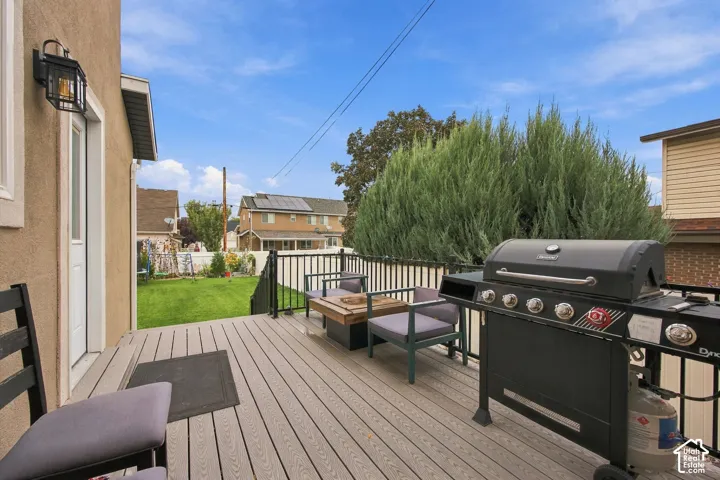Elevated composite deck featuring black metal railing, wall-mounted exterior lighting, and a manicured backyard