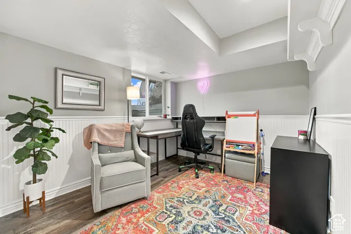 Room featuring wood-finish flooring, white beadboard wainscoting, neutral wall paint, and a built-in recessed shelf