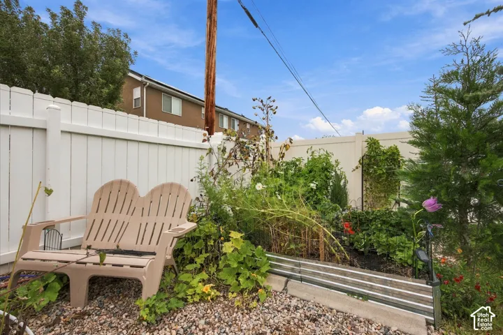 Rear yard featuring a white vinyl privacy fence, raised corrugated metal garden beds, and gravel landscaping