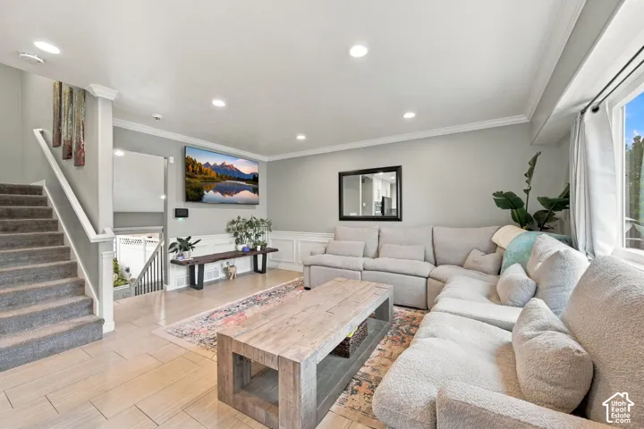 Open-concept living space featuring ceramic tile flooring, crown molding, recessed lighting, and wall wainscoting