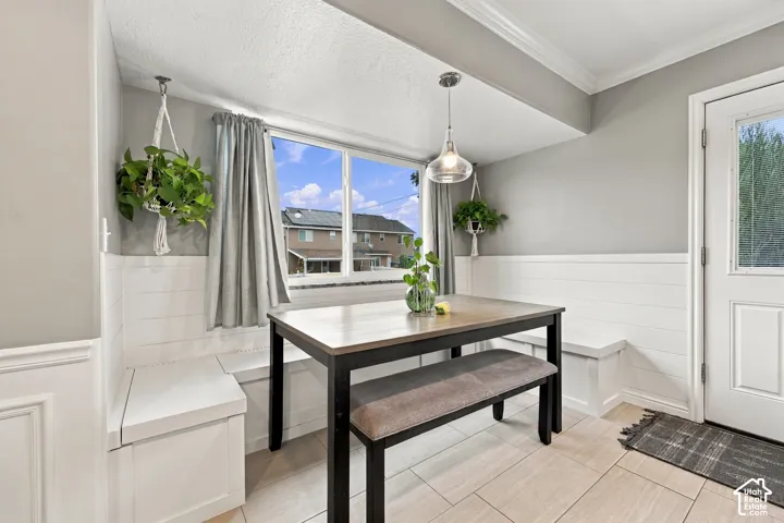 Built-in white bench seating featuring horizontal shiplap detailing, large picture window, and hanging glass pendant light