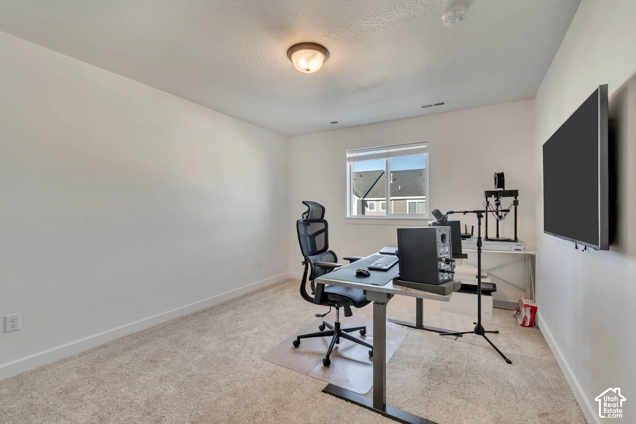 Carpeted room with a single window and flush mount ceiling light fixture