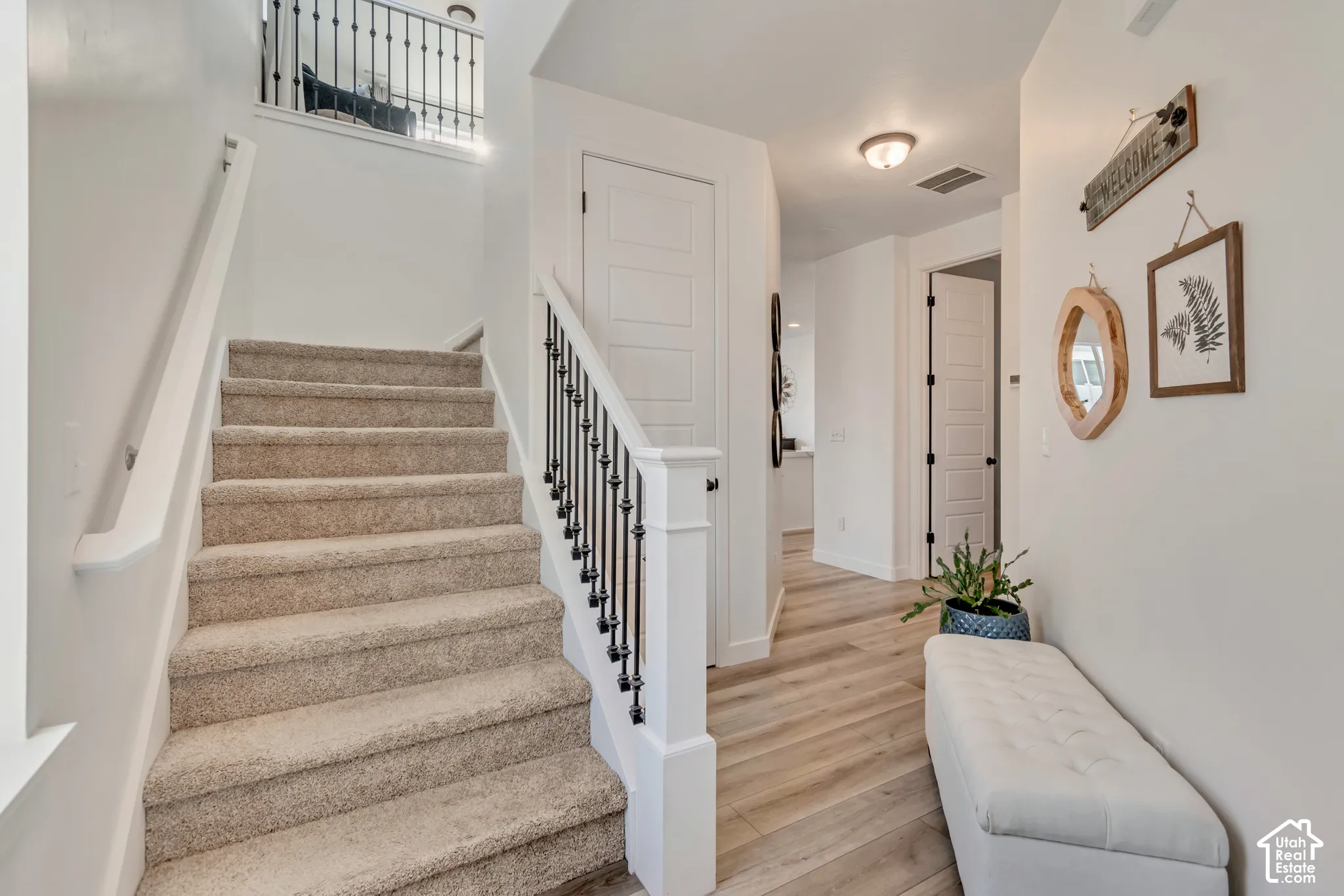 Carpeted staircase with wrought iron balusters, wood-finish flooring, white paneled doors, and recessed lighting