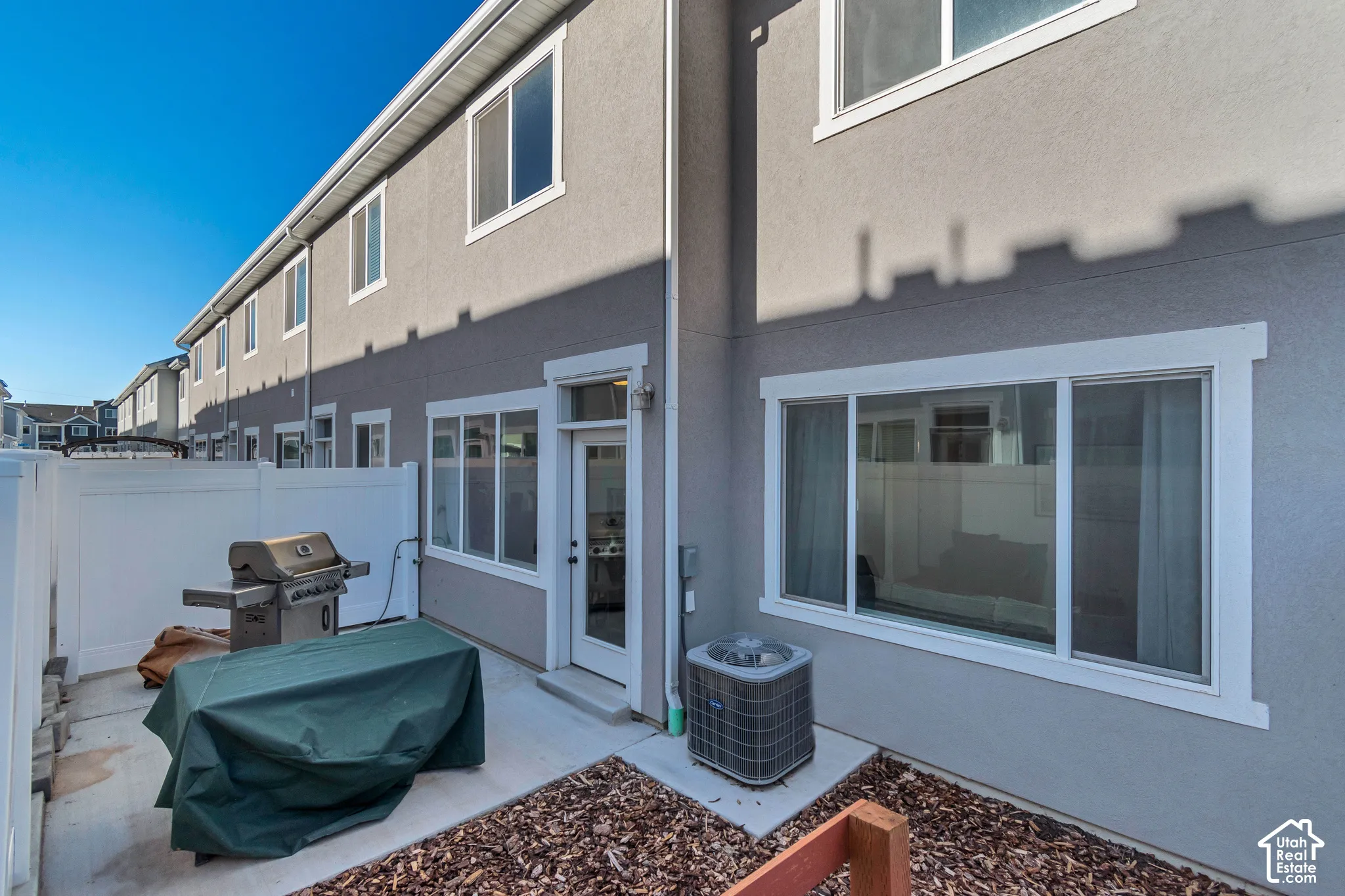 Private patio with concrete surfacing, white vinyl fencing, and a glass-paneled exterior door