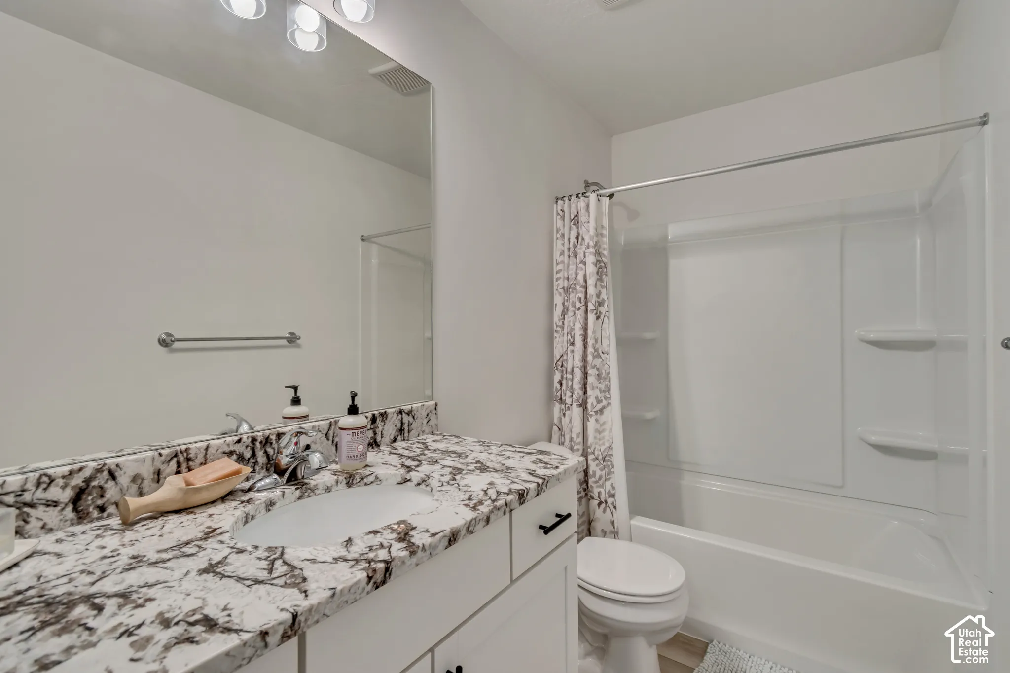 White vanity with a stone-finish countertop and integrated sink