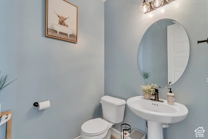 Pedestal sink with bronze-finish faucet, oval wall mirror, and three-light vanity fixture