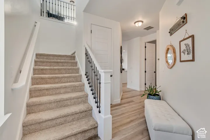 Carpeted staircase with wrought iron balusters, wood-finish flooring, white paneled doors, and recessed lighting