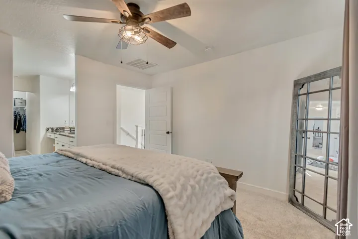 Carpeted room with a ceiling fan featuring wood-finish blades and a caged light fixture