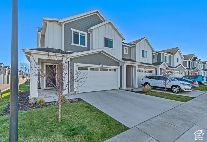 Modern townhome with gabled roof lines, attached garage, concrete driveway, and covered front porch