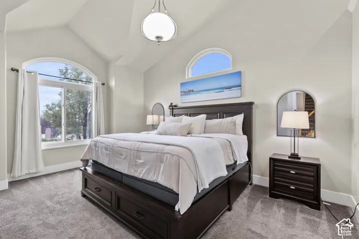 Vaulted ceiling featuring an arched window, a secondary arched transom window, wall-to-wall carpeting, and a central pendant light fixture