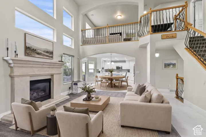 Double-height ceilings with stacked windows, stone-surround fireplace, arched architectural detailing, and custom staircase with metal spindle railings