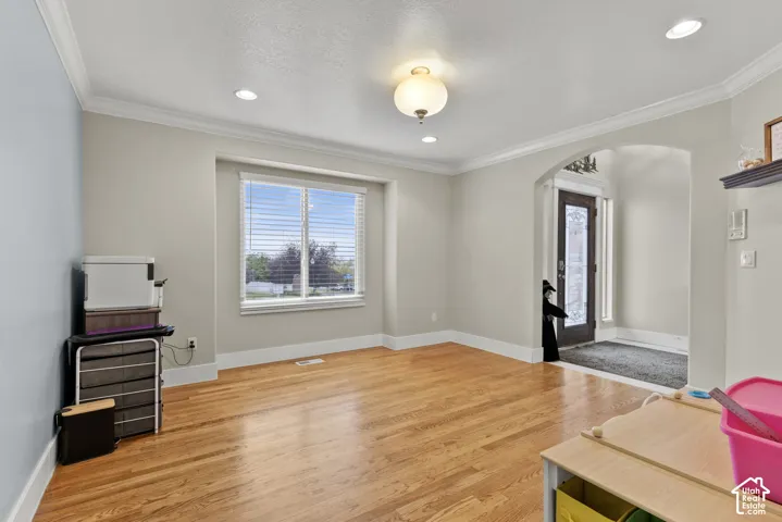 Interior space featuring wood-finish flooring, crown molding, recessed lighting, and an arched entryway