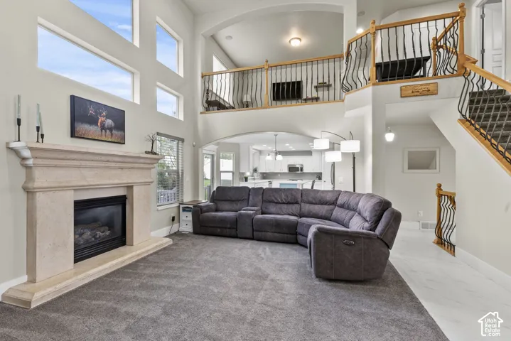 Two-story living area featuring a stone-surround fireplace, vaulted ceilings, multi-tier windows, and a railed staircase with wrought-iron balusters