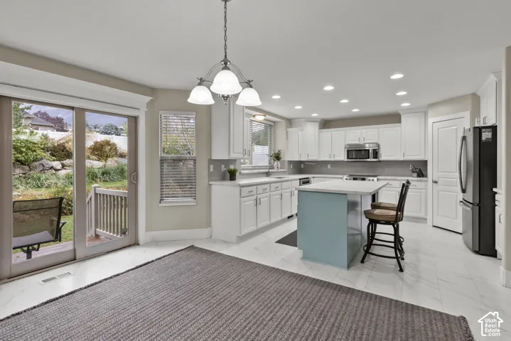 Kitchen featuring white cabinetry, a center island with a blue base, neutral stone-finish countertops, recessed lighting, and a sliding glass door