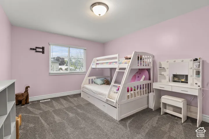 Bedroom featuring neutral-toned carpeting, a dual-pane sliding window, and a flush-mount overhead light fixture