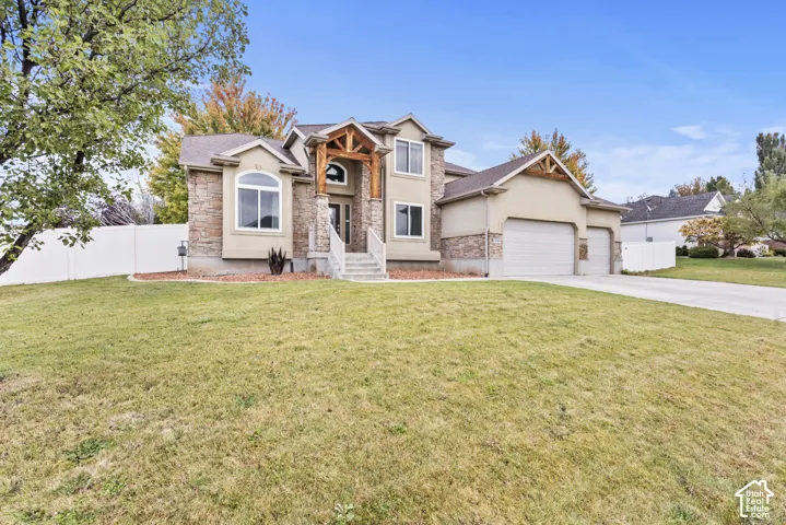 Two-story exterior featuring stone veneer accents, timber-frame entryway detail, a concrete driveway, a three-car garage, and vinyl privacy fencing