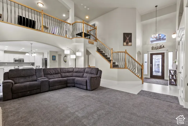 Double-height ceiling, open staircase featuring wood handrails and wrought iron balusters, arched architectural elements, and glass-panel entry door with sidelights