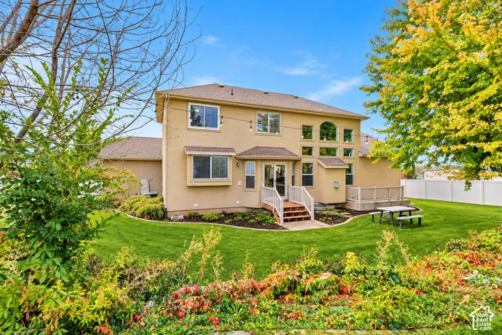Stucco exterior featuring tiered rooflines, arched windows, multi-level exterior decking, and landscaped grounds with mature trees