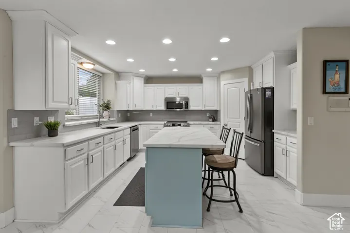 Kitchen featuring white cabinetry, center island with stone-finish countertop, stainless steel appliances, recessed lighting, and tile flooring