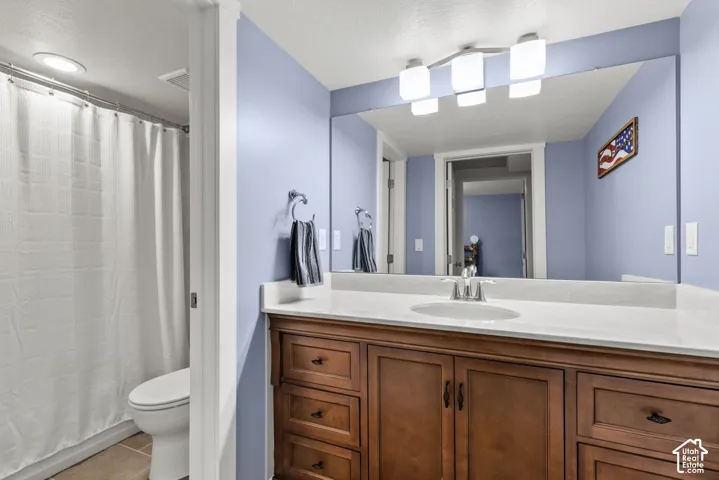 Bathroom vanity featuring a light-toned countertop, integrated basin, and dark wood-finish cabinetry, complemented by a large wall-mounted mirror and a three-light vanity fixture