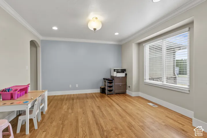 Room featuring wood-finish flooring, crown molding, recessed lighting, a semi-flush mount light fixture, and a bay window