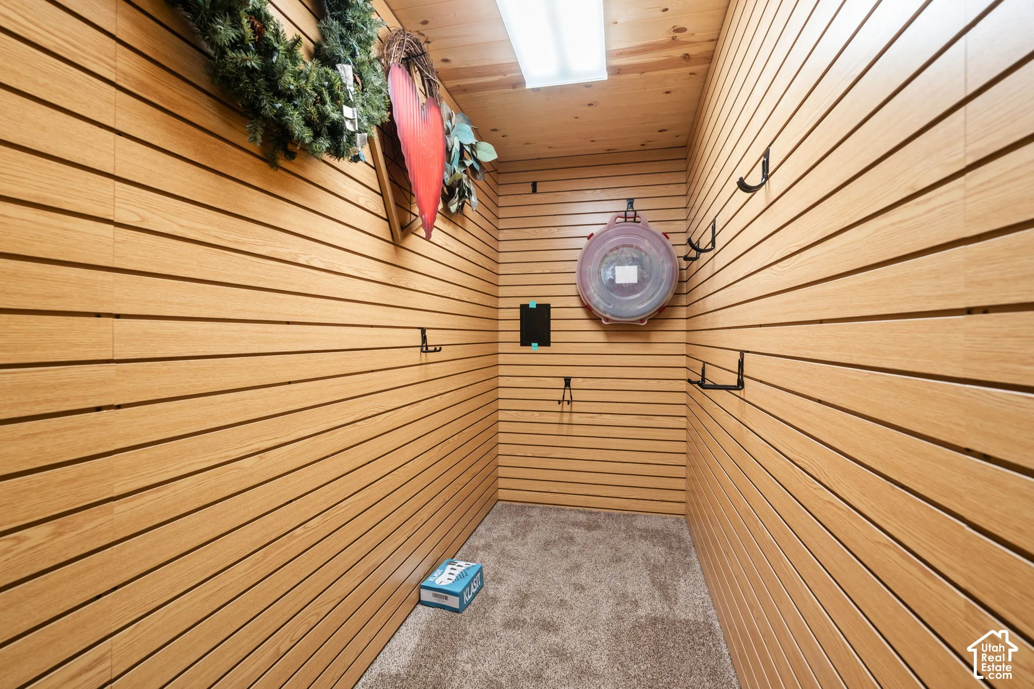 Plenty of storage! Wood-finish slat wall paneling, integrated wall-mounted hardware, wood-plank ceiling, and carpeted flooring