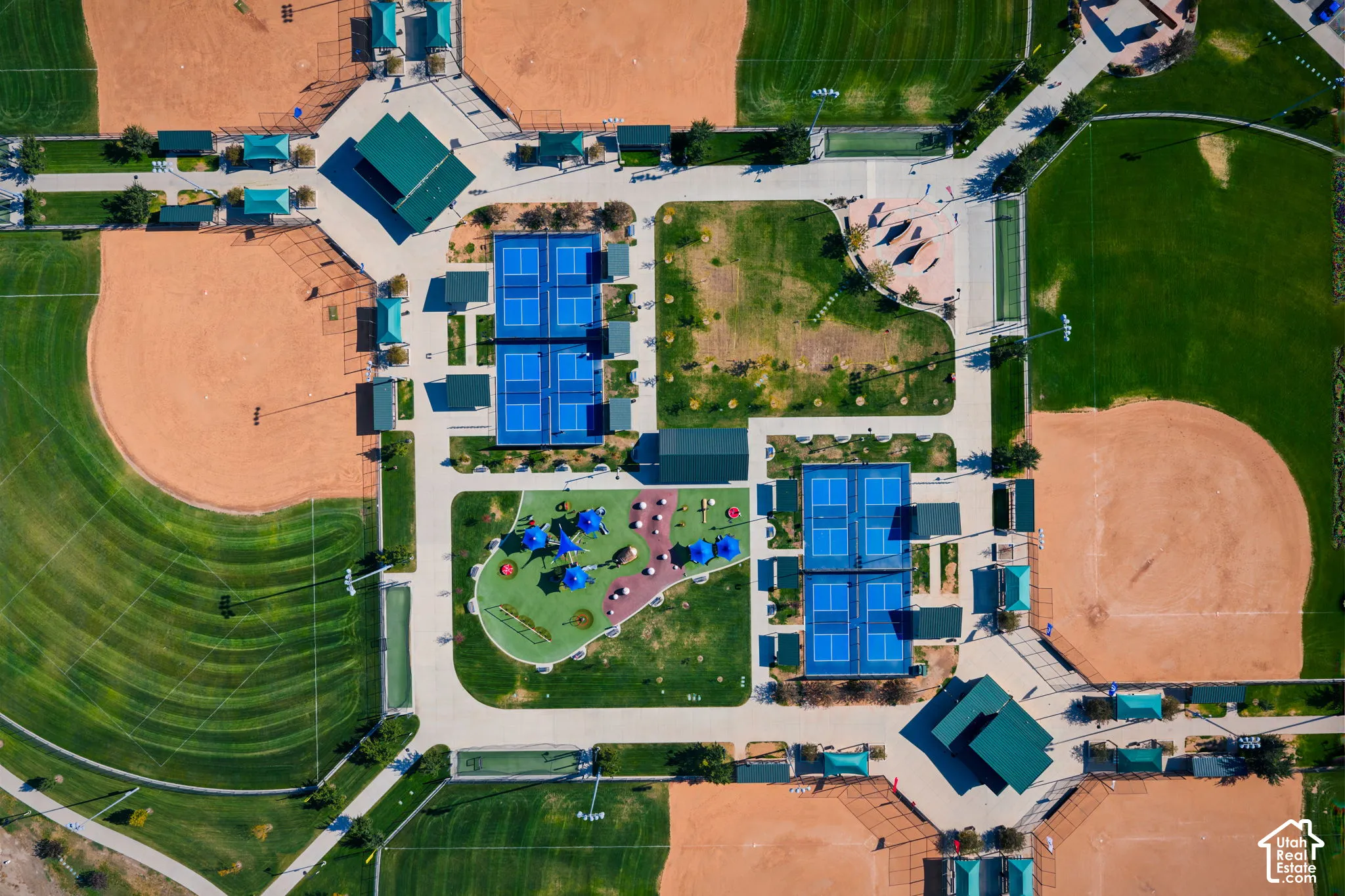 Public recreational complex featuring four baseball diamonds, paved pathways, multiple tennis courts, and a central parking area