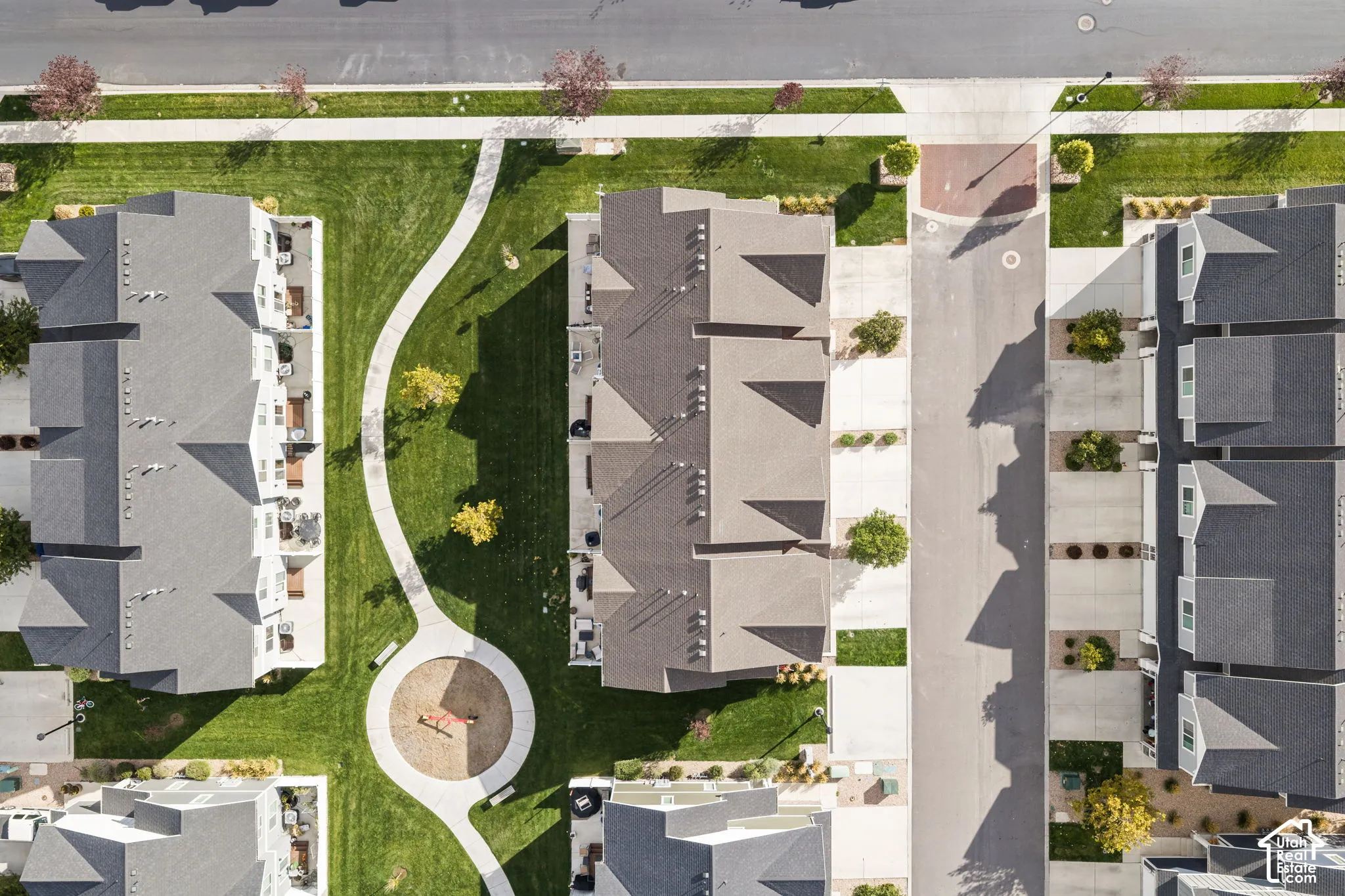 Aerial perspective featuring multi-story residential structures, paved concrete driveways, manicured common lawn areas, and concrete pedestrian walkways