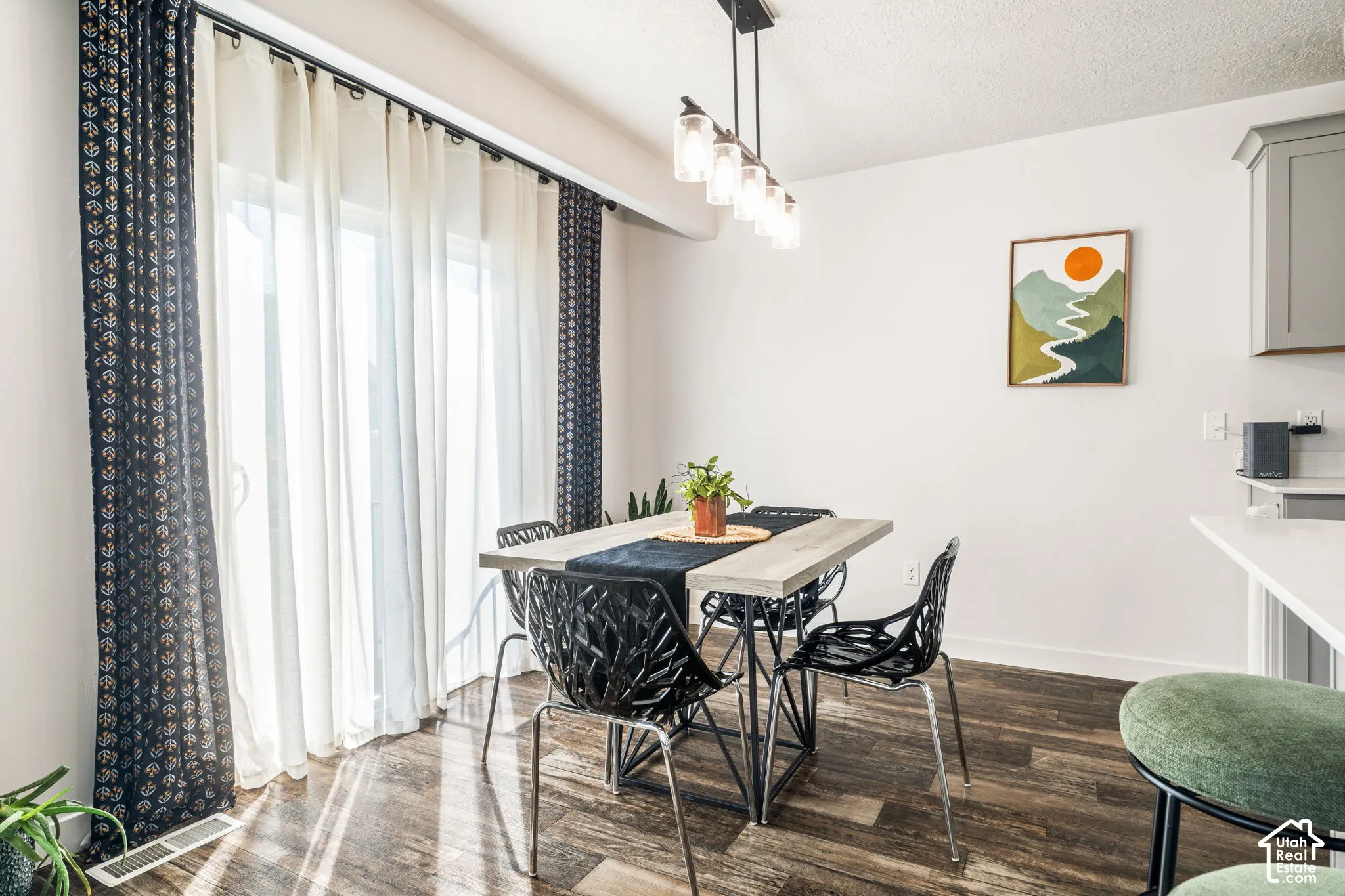 Sliding glass doors featuring floor-to-ceiling glass, wood-finish flooring, and a multi-pendant light fixture with clear glass shades
