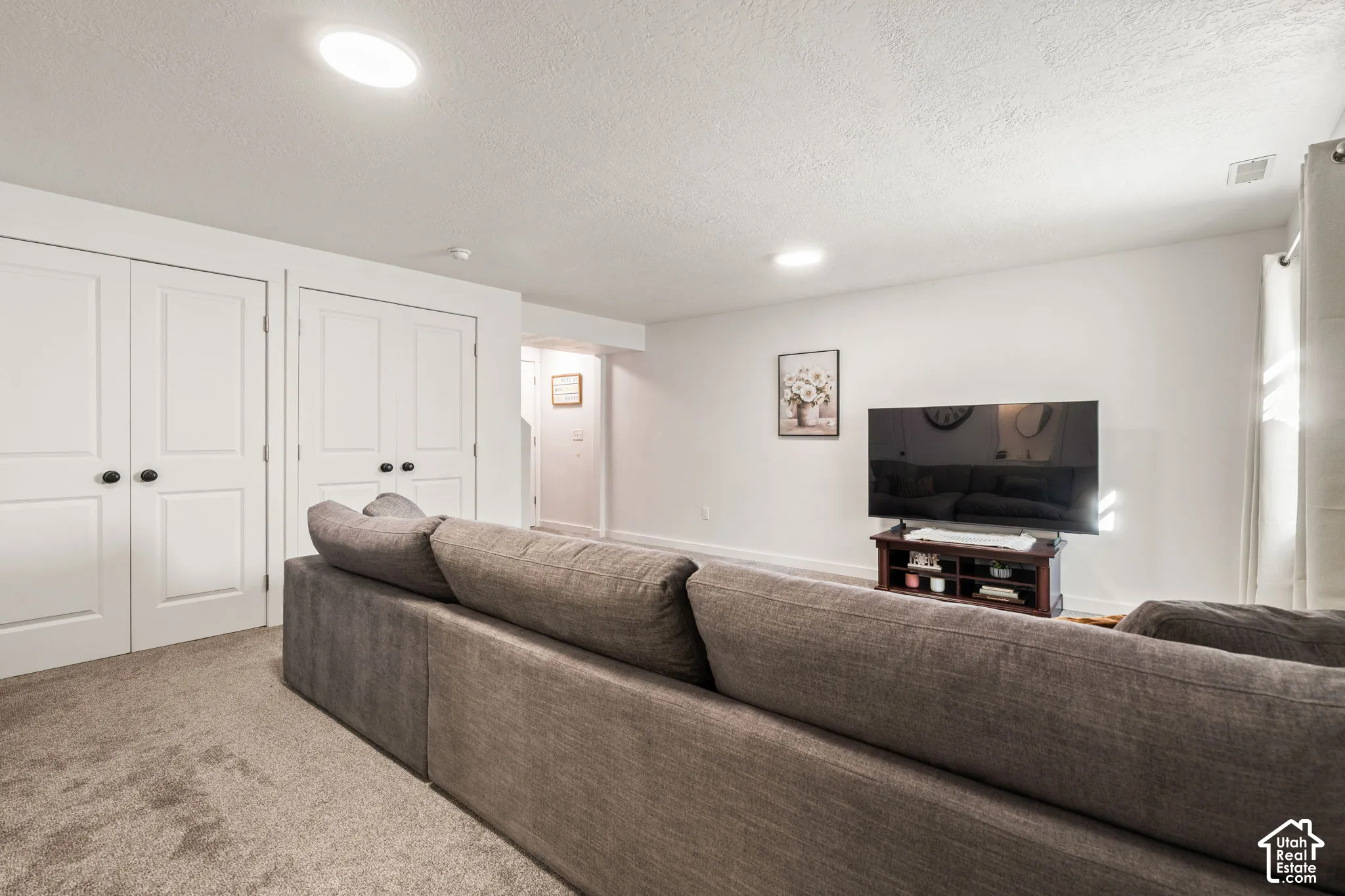 Neutral-toned carpeting, dual sets of white interior paneled doors with matte black hardware, and integrated recessed ceiling lighting
