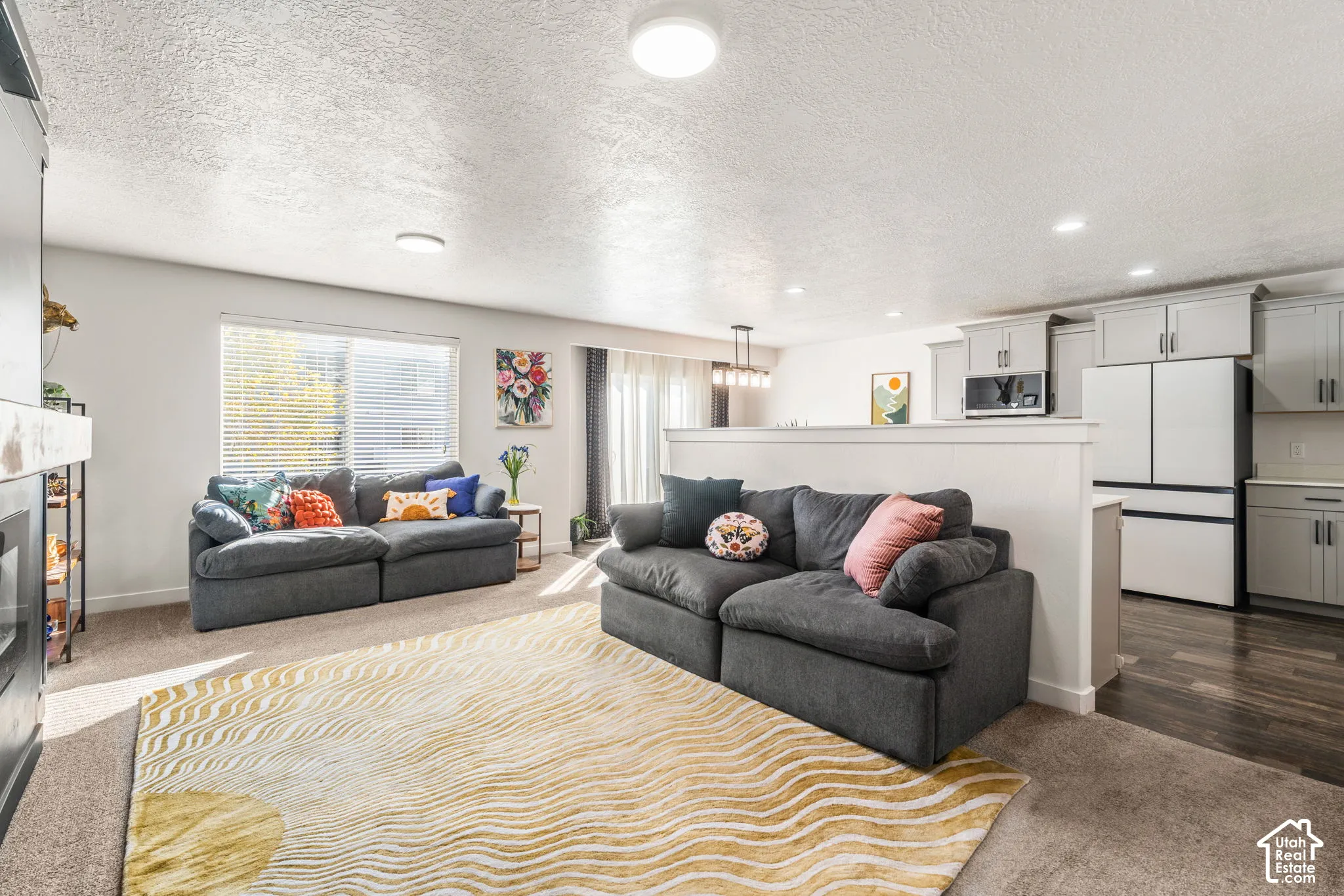Open-concept interior featuring light gray shaker-style cabinetry, dark wood-finish flooring, recessed lighting, and an abundance of natural light.